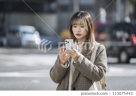 A woman in her 20s operating a smartphone in the city A woman in her 20s operating a smartphone in the city 113075443