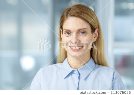 Confident professional woman with a friendly smile in a corporate office environment, showcasing leadership and positivity. 113076036