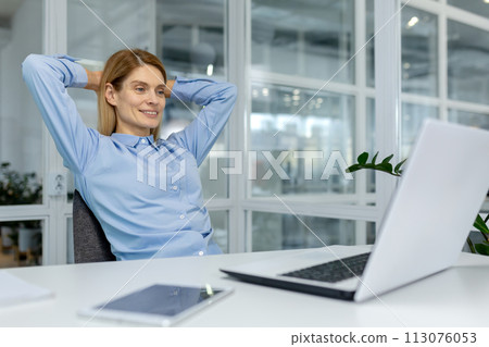 A professional woman takes a moment to relax in her bright office, exuding calmness and confidence behind her laptop. A professional woman takes a moment to relax in her bright office, exuding calmness and confidence behind her laptop. 113076053