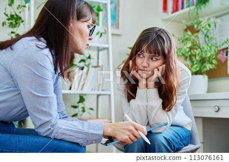 Sad, serious teenage girl at session in office of mental counselor 113076161
