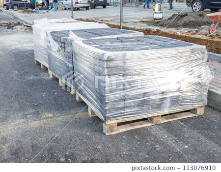 Pavement repair. Laying out paving stones. Paving stones in pallets in polyethylene. Pavement repair. Laying out paving stones. Paving stones in pallets in polyethylene. 113076910
