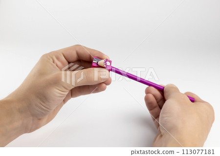 Pencil sharpener. Hands sharpen a pencil on a white background. 113077181