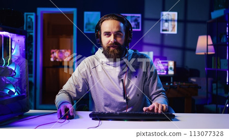 Excited esports player recording playing videogames in front of audience during livestream, providing engaging commentary while battling opponents. Pro gamer participating in gaming competition 113077328