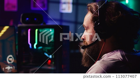 Man using headphones microphone to talk with teammates while playing FPS videogame with gun shooting laser bullets. Gamer chatting with internet friends while enjoying SF game, close up 113077407