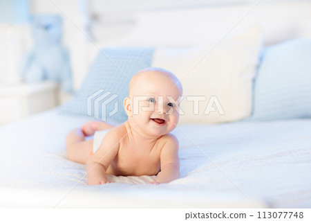 Baby boy on white bed 113077748