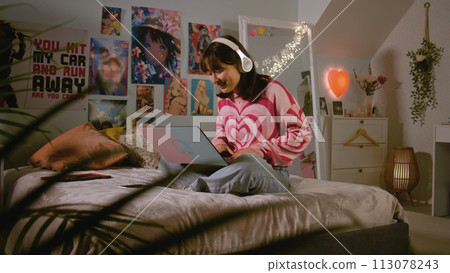 Asian teenage girl listens to music, chats and surfs the Internet on laptop 113078243