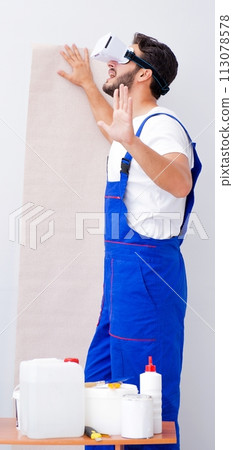 Man with VR glasses gluing wallpaper Man with VR glasses gluing wallpaper 113078578