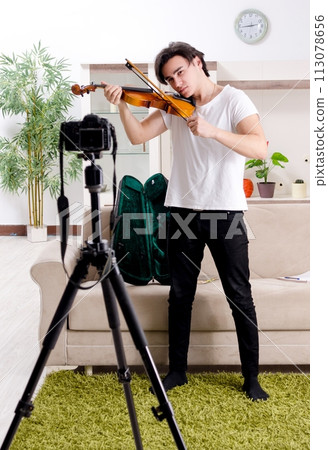 Young male blogger playing violin at home Young male blogger playing violin at home 113078656