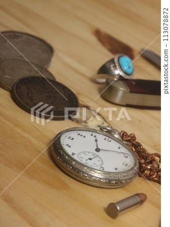 Pocket Watch With Silver Coins and Knife on Wooden Table 113078872