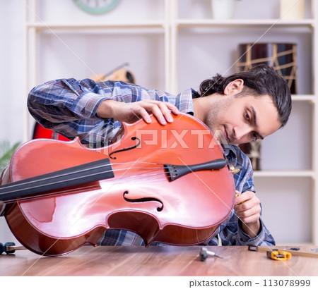 Young handsome repairman repairing cello 113078999