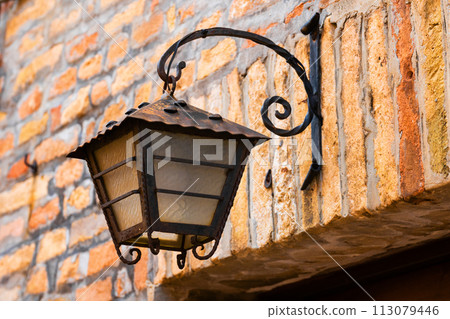 Old vintage style street lamp hanging at the street in city. Light lamp 113079446