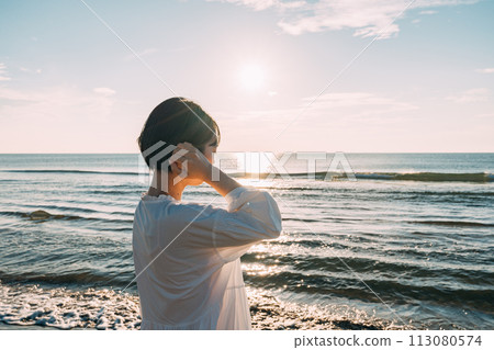Sun setting over the sea and silhouette of a woman 113080574