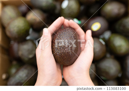 Child's hand holding avocado 113083100
