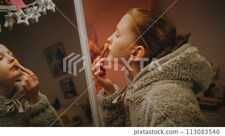 Close up of teenage girl doing makeup in cozy bedroom Close up of teenage girl doing makeup in cozy bedroom 113083540