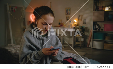 Young girl in headphones uses smartphone, then talks with friend Young girl in headphones uses smartphone, then talks with friend 113083553