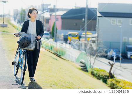 Middle-aged woman commuting to work on a bicycle Middle-aged woman commuting to work on a bicycle 113084156