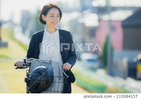 Middle-aged woman commuting to work on a bicycle Middle-aged woman commuting to work on a bicycle 113084157