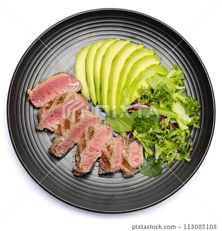 grilled cooked piece of tuna fillet with sliced avocado and salad on black ceramic plate grilled cooked piece of tuna fillet with sliced avocado and salad on black ceramic plate 113085108