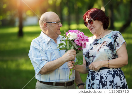 Happy elderly couple with flowers. Handsome man and woman senior citizens. Husband and wife of old age for a walk. 113085710