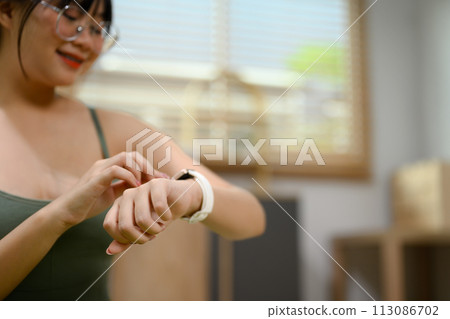 Active woman checking time or results on smartwatch after working out at home 113086702