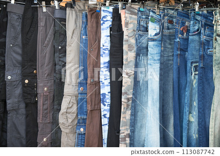 Jeans hang in a row. Pants made of woven fabric Jeans hang in a row. Pants made of woven fabric 113087742