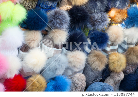 Knitted hats with colored pom-poms 113087744