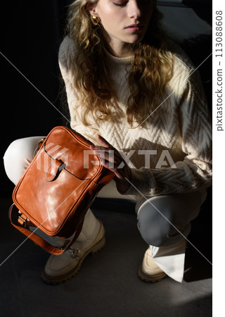 beautiful curly blond hair woman posing squatting with a small brown near grey wall 113088608
