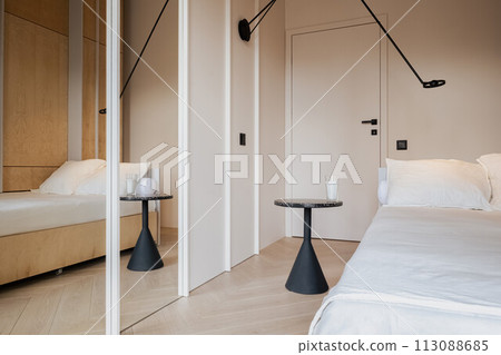Bedroom with wooden bed, tables, mirror. Comfortable hardwood flooring Bedroom with wooden bed, tables, mirror. Comfortable hardwood flooring 113088685