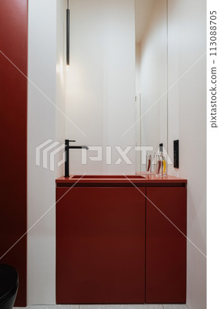 a bathroom with a red sink , mirror and toilet 113088705