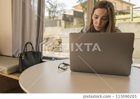 Corporate woman working tirelessly on her laptop in the hotel bar during a business trip 113090283