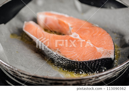 Frying salmon steak on parchment paper with butter 113090362