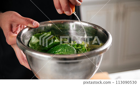 Chef washing spinach leaves in bowl 113090530