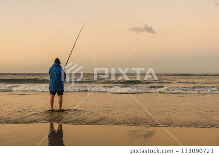 Fisherman in blue jacket fishing on the beach shore in the afternoon. Copy space Fisherman in blue jacket fishing on the beach shore in the afternoon. Copy space 113090721