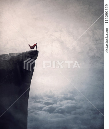 Superhero with cape stands brave on edge of a cliff above the clouds searching determined at horizon with hand up to forehead. Powerful hero conceptual scene Superhero with cape stands brave on edge of a cliff above the clouds searching determined at horizon with hand up to forehead. Powerful hero conceptual scene 113090869