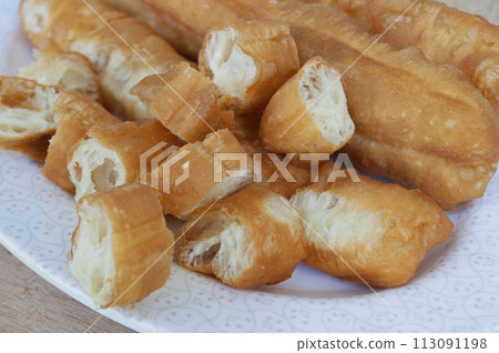 Close up view of cut cakoi or youtiao cake on white plate. Asian food concept Close up view of cut cakoi or youtiao cake on white plate. Asian food concept 113091198