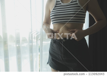 Women body fat belly. Obese woman hand holding excessive belly fat. diet lifestyle concept to reduce belly and shape up healthy stomach muscle. 113092043