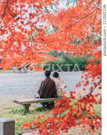 A couple in yukata sitting in an autumn park A couple in yukata sitting in an autumn park 113092196