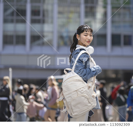 Young woman looking at camera with a backpack on her shoulder 113092309