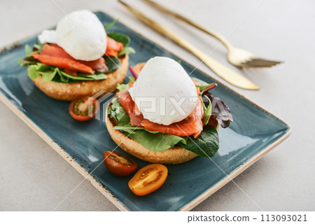Eggs Benedict with salad leafs, salmon and fresh cherry tomato Eggs Benedict with salad leafs, salmon and fresh cherry tomato 113093021