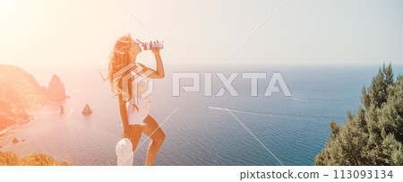 Woman summer travel sea. Happy tourist enjoy taking picture outdoors for memories. Woman traveler posing over sea bay surrounded by volcanic mountains, sharing travel adventure journey 113093134