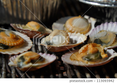 various types of clams are grilled on a grill and then dipped in seasoning and eaten. 113093942