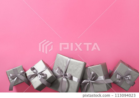 Monochrome gray gift boxes with silver ribbons on pink background. Copyspace Monochrome gray gift boxes with silver ribbons on pink background. Copyspace 113094023