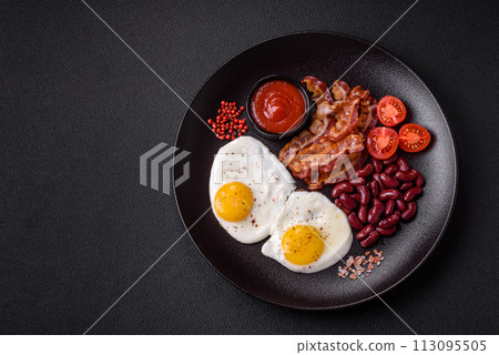 English breakfast with fried eggs, bacon, beans, tomatoes, spices and herbs 113095505