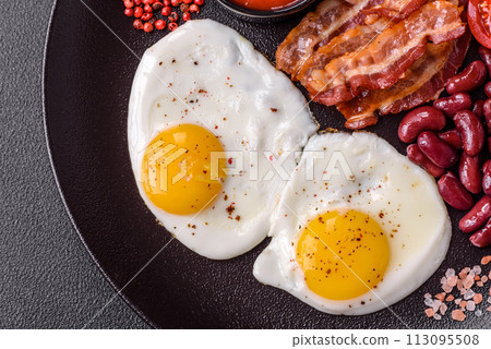 English breakfast with fried eggs, bacon, beans, tomatoes, spices and herbs 113095508