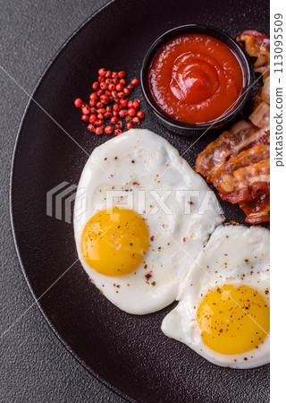 English breakfast with fried eggs, bacon, beans, tomatoes, spices and herbs English breakfast with fried eggs, bacon, beans, tomatoes, spices and herbs 113095509