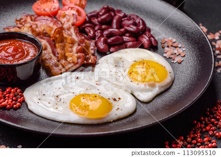 English breakfast with fried eggs, bacon, beans, tomatoes, spices and herbs English breakfast with fried eggs, bacon, beans, tomatoes, spices and herbs 113095510