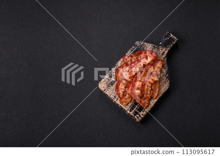 Delicious fresh fried bacon with salt and spices on a dark background Delicious fresh fried bacon with salt and spices on a dark background 113095617
