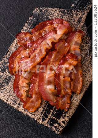 Delicious fresh fried bacon with salt and spices on a dark background 113095624