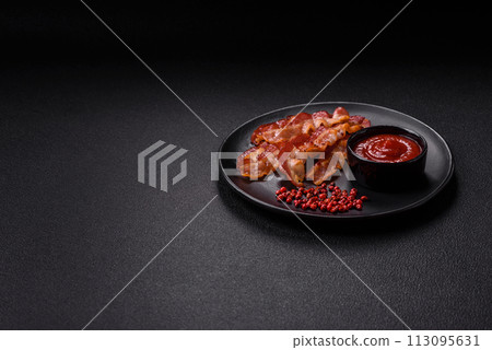 Delicious fresh fried bacon with salt and spices on a dark background 113095631