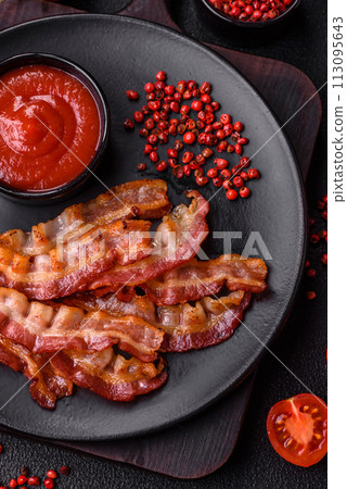 Delicious fresh fried bacon with salt and spices on a dark background Delicious fresh fried bacon with salt and spices on a dark background 113095643